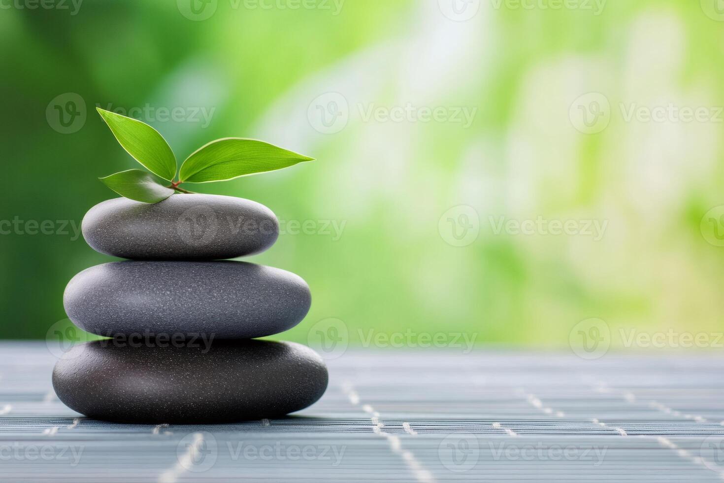 Stack of smooth grey stones balancing with green leaf on top symbolizing growth photo