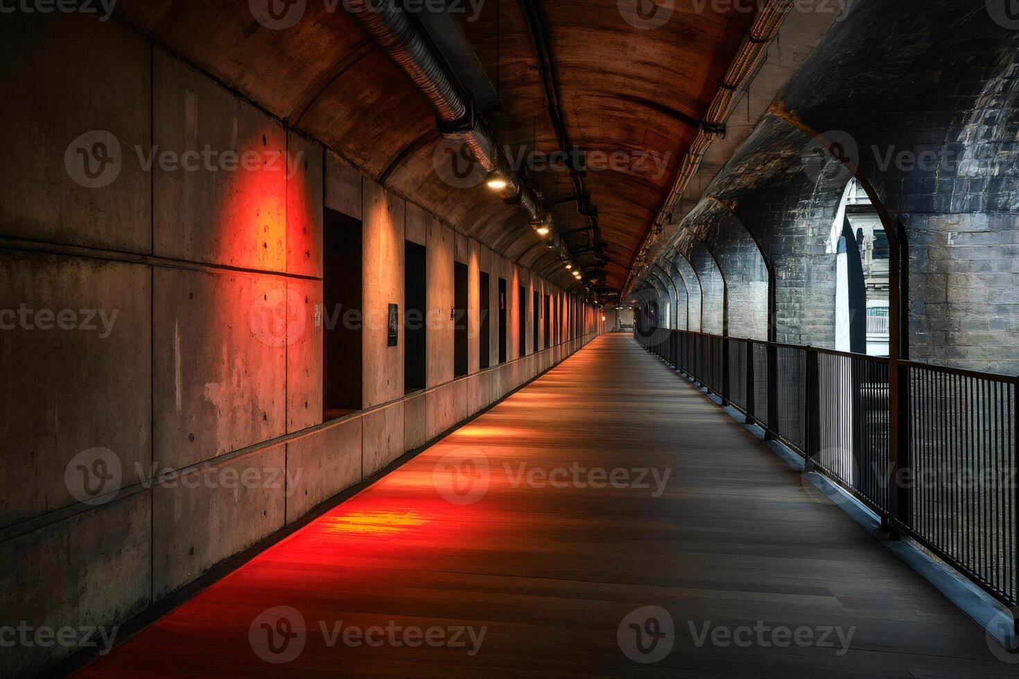 Red lights illuminating long concrete corridor with arches and railing photo