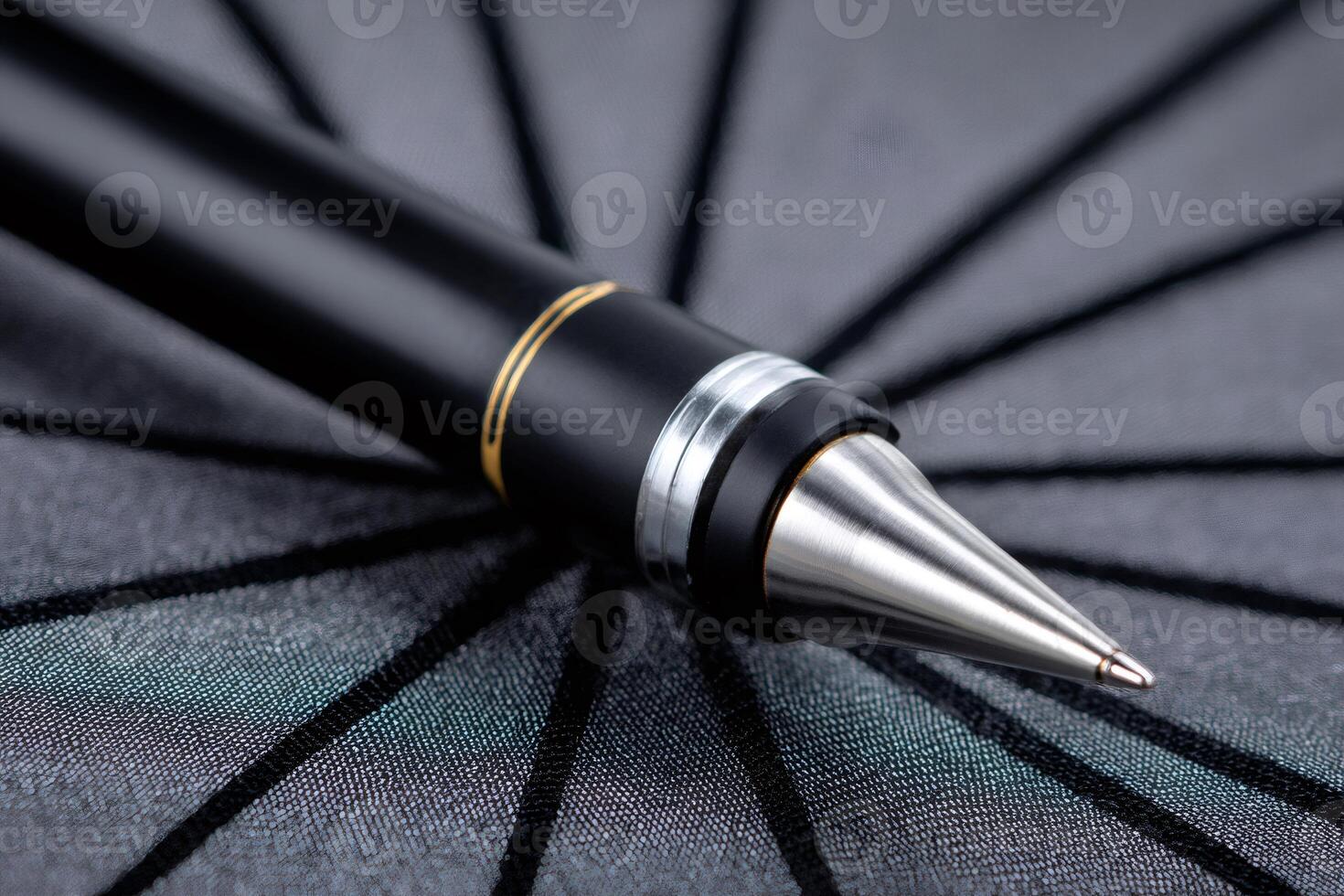 Elegant black and gold pen resting on dark gray surface photo