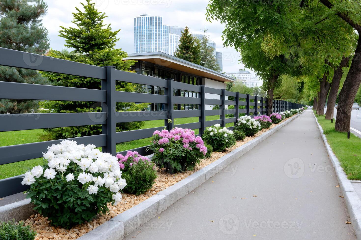 Modern fence bordering a pedestrian walkway with blooming flowers and trees photo