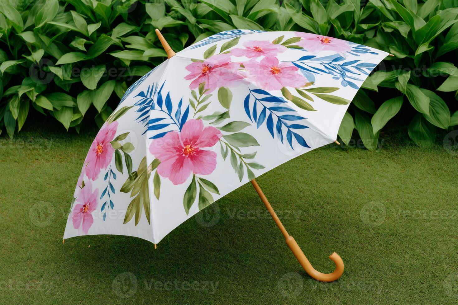 Elegant white umbrella with pink flowers and blue leaves resting on green grass photo