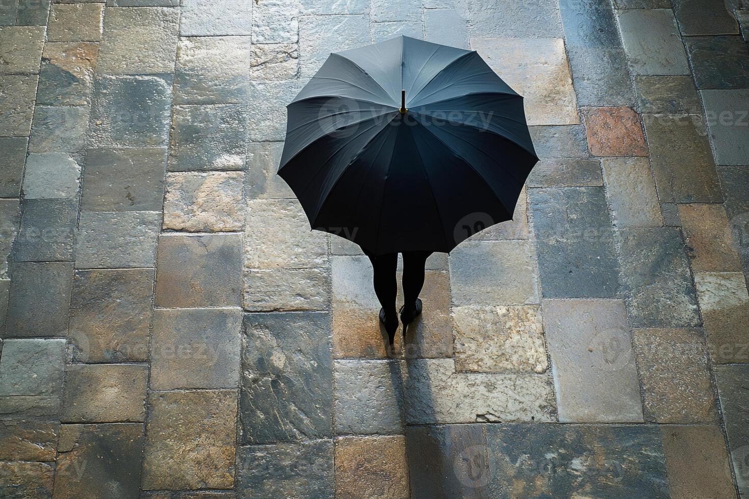 Businesswoman holding umbrella on wet stone pavement during rainy day photo