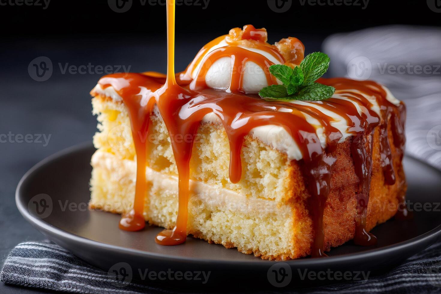 Caramel sauce pouring over a slice of cake with cream and mint photo