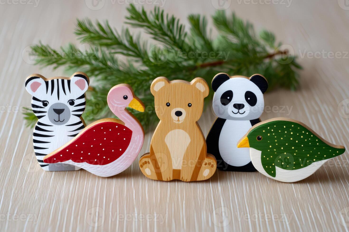 Cute wooden animal toys placed on a table near a fir branch photo