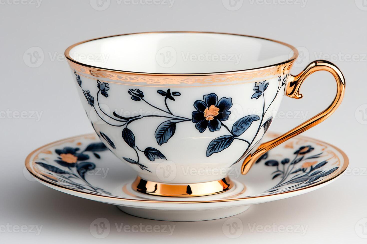 Elegant porcelain teacup and saucer with gold decorations and blue floral pattern sitting on white background photo