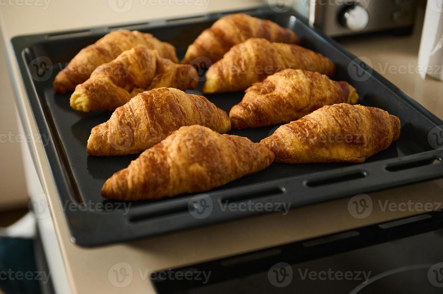 Freshly Baked Golden Croissants Cooling on Baking Sheet in Kitchen photo