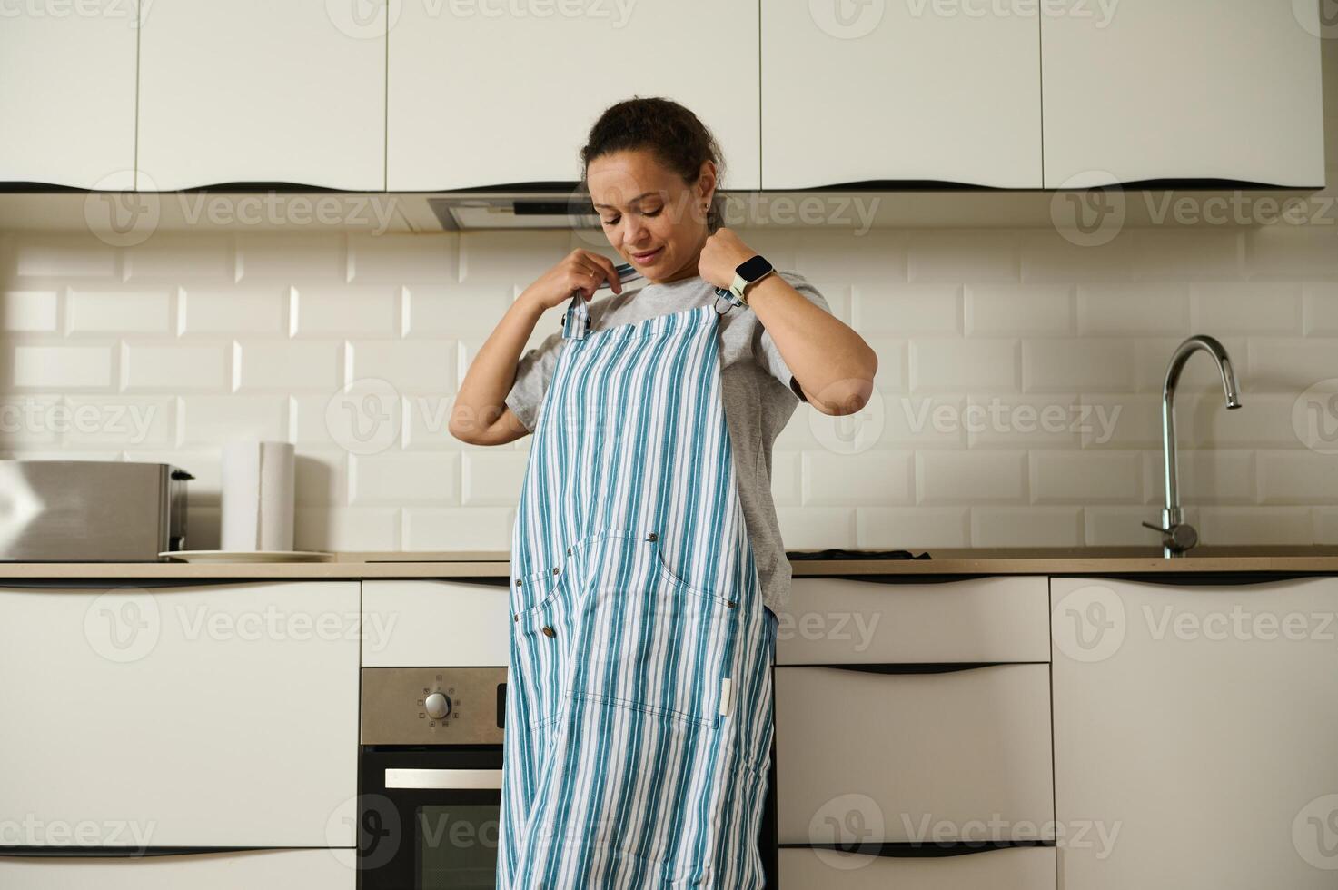 Woman Adjusting Apron in a Modern, Minimalistic Kitchen Setting photo