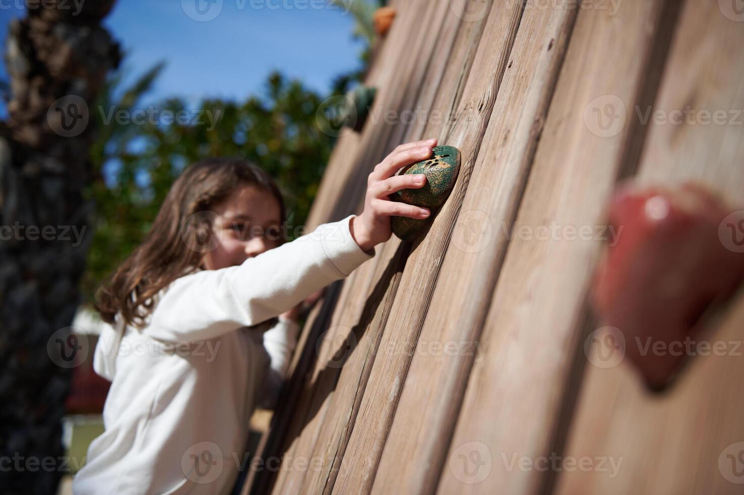 Young Girl Engaging in Outdoor Climbing Activity on a Wooden Wall photo