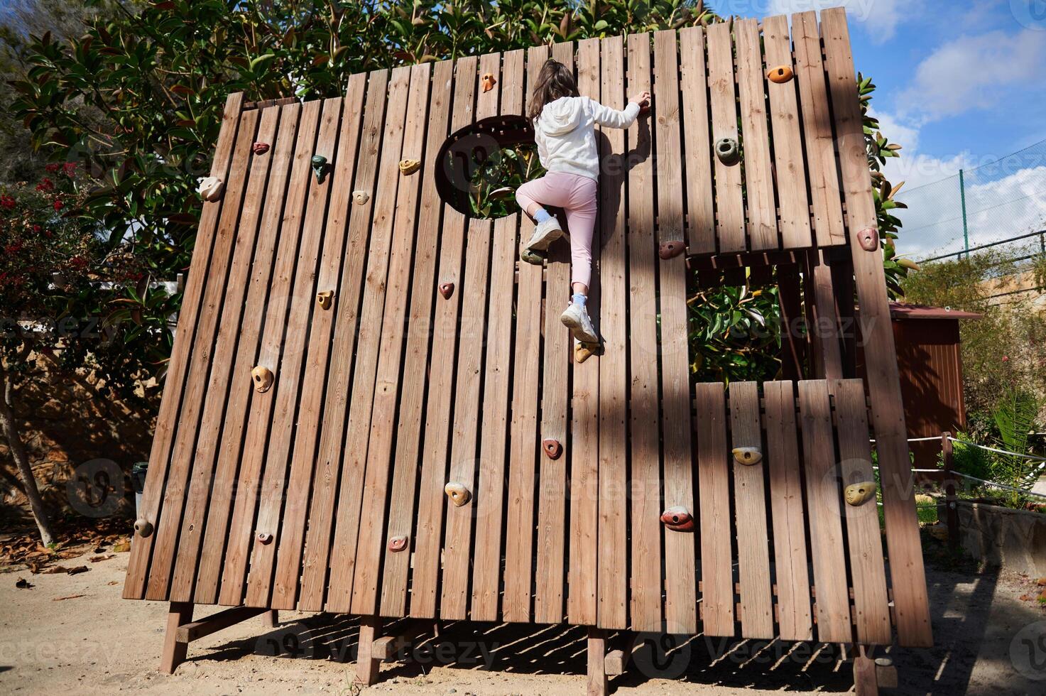 Young Girl Climbing Play Structure Outdoors on a Sunny Day photo