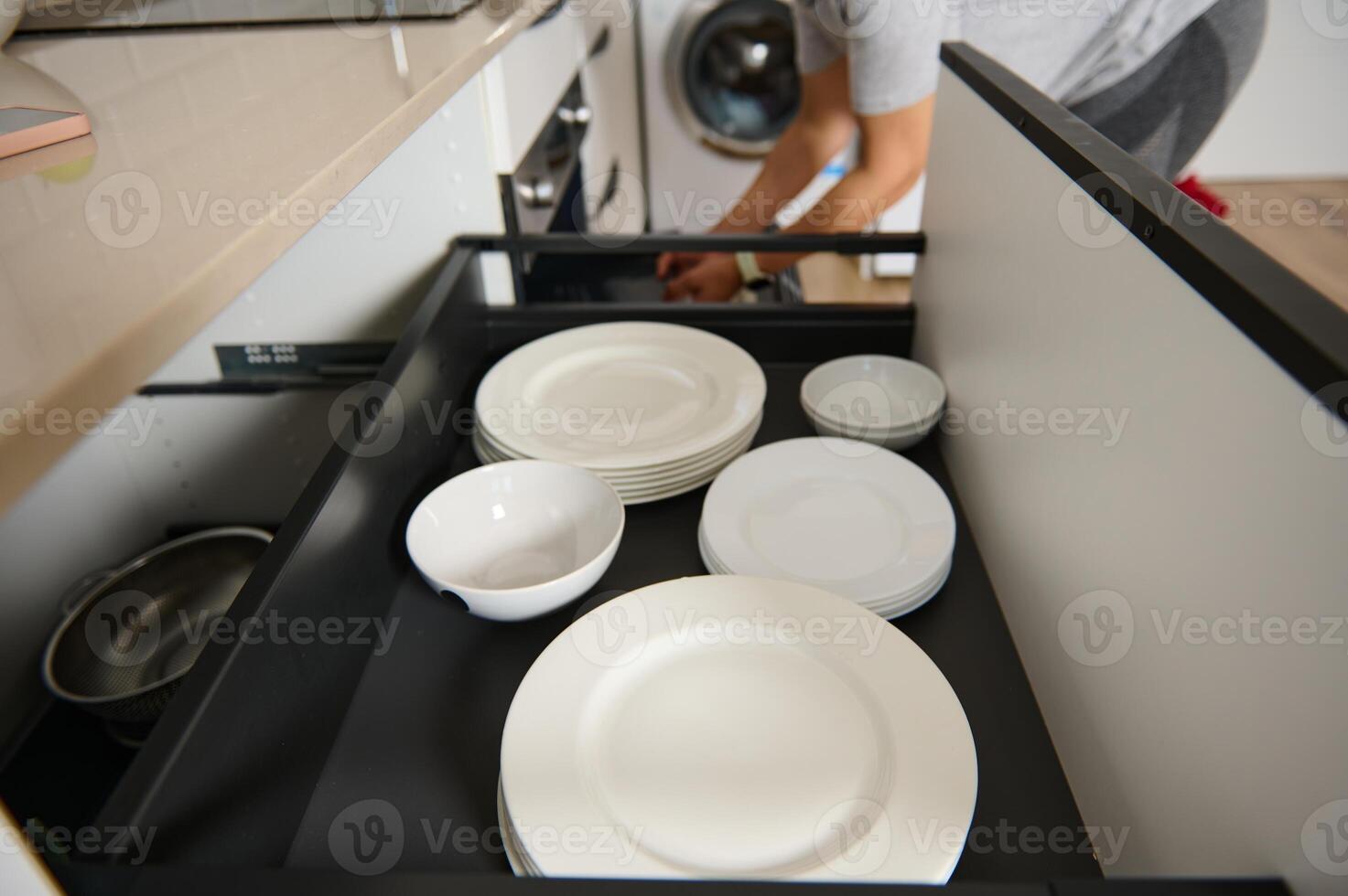 Organized Kitchen Drawer With Plates and Bowls Being Restocked by an Individual photo