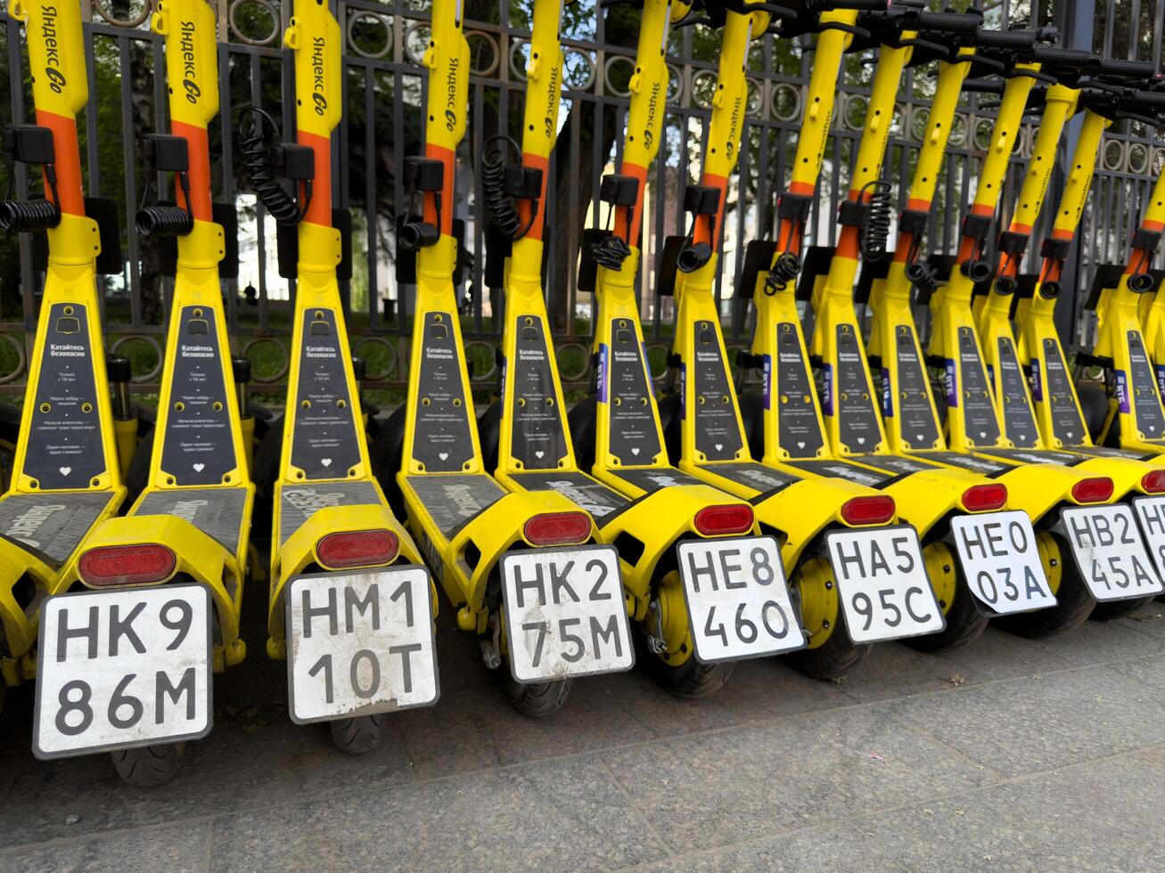 Moscow, Russia, April 24, 2025. Close view of Yandex Go electric scooters parked in row, highlighting mandatory license plates required for legal use on city streets photo