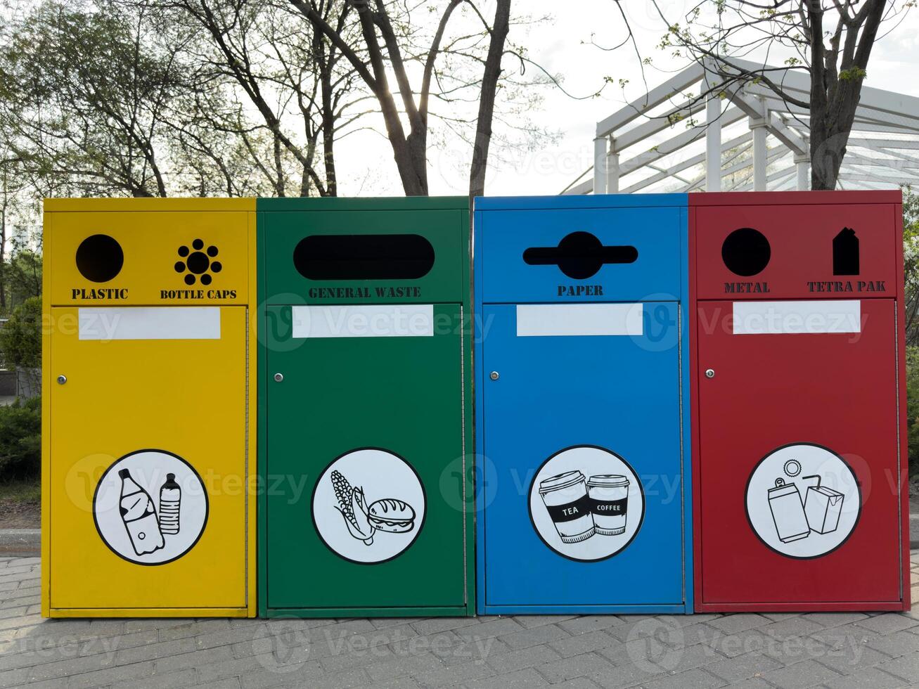 Colorful recycling bins for plastic, general waste, paper, and metal stand side by side in an urban park, promoting environmental responsibility and sustainable waste separation photo