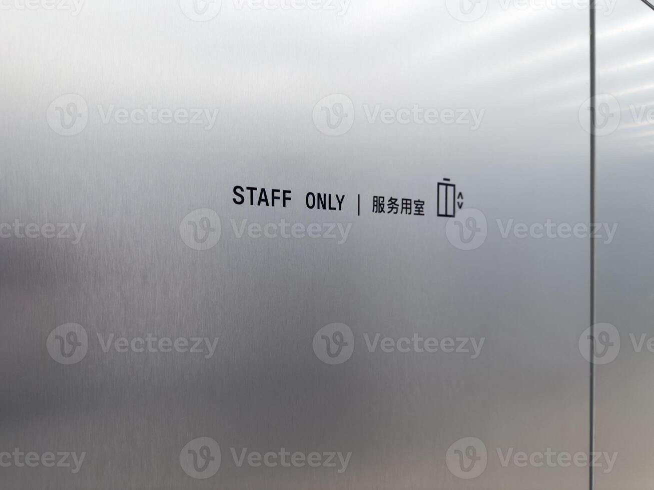 Close up of bilingual staff only sign with elevator icon in English and Chinese. Concept of restricted area, employee access, international navigation, logistics and facility management photo