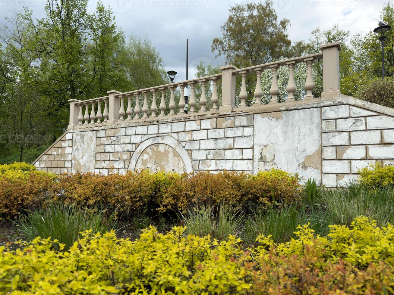 Restoration of a balustrade and stone wall with staircase in a public park, showing peeling paint and renewed landscaping as part of ongoing park improvement and renovation efforts photo