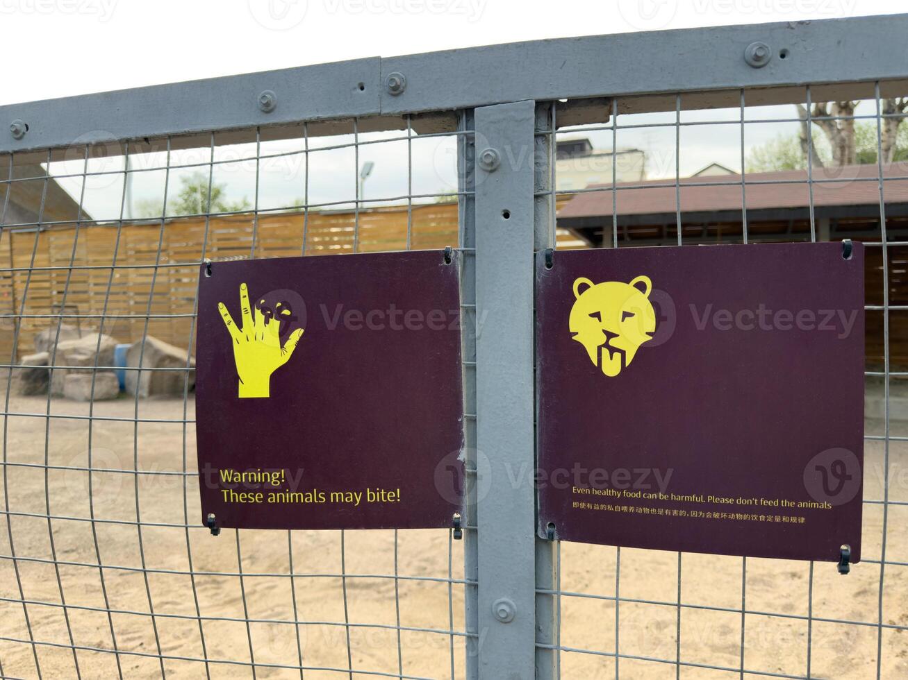 Warning signs on enclosure with dangerous animal in zoo. Inscription on sign about warning about biting animal. Concept of safety rules of visiting zoo. Do not feed the animals in cage, they can bite photo