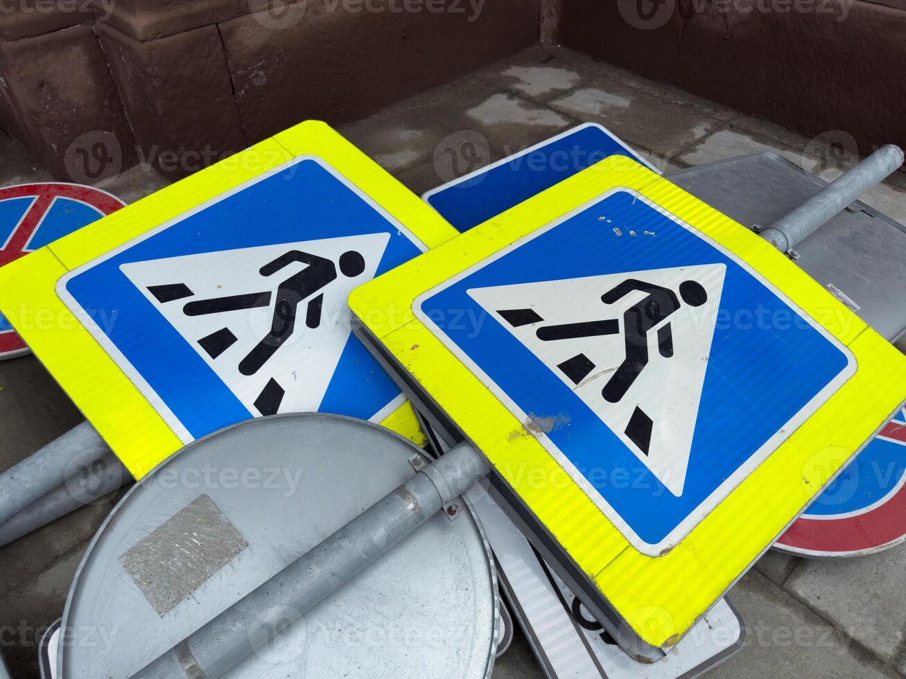 Decommissioned pedestrian crossing signs stacked on the ground as part of an urban infrastructure update. Symbolic representation of modernization and street renovation in the city photo
