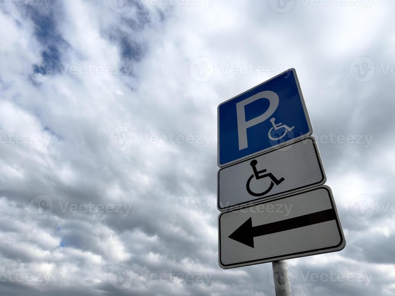 Handicap parking sign with directional arrow on cloudy day, indicating accessible parking for people with disabilities, promoting inclusion and barrier free infrastructure photo