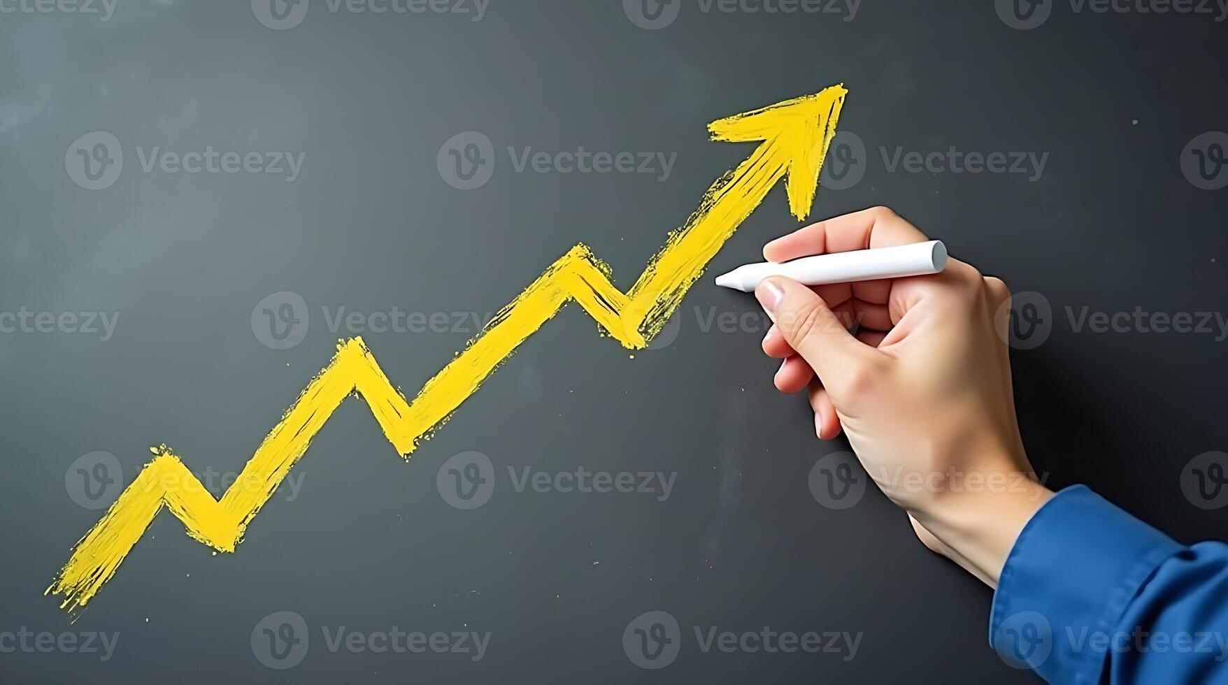 Hand drawing a yellow upward arrow on a dark surface represents growth and success photo