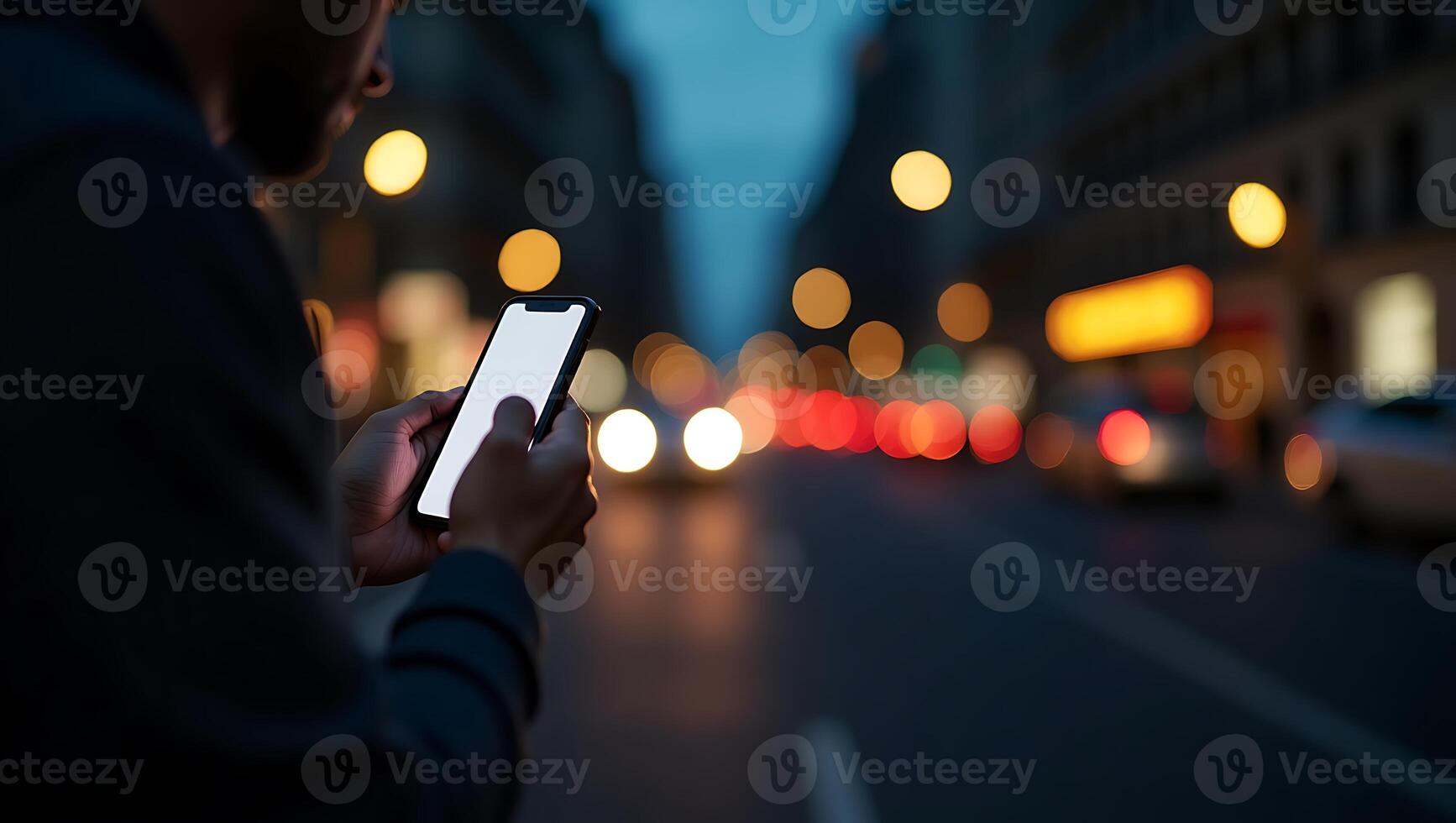 Person using smartphone outdoors at night with city lights in the background photo
