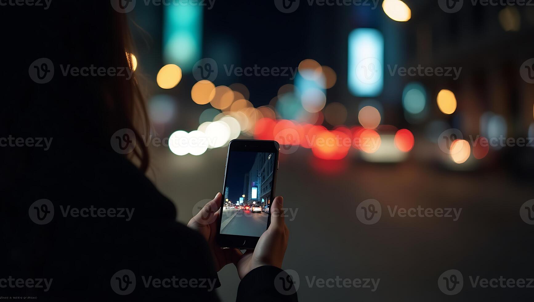 Person capturing night city scene with a smartphone focusing on lights and reflections photo