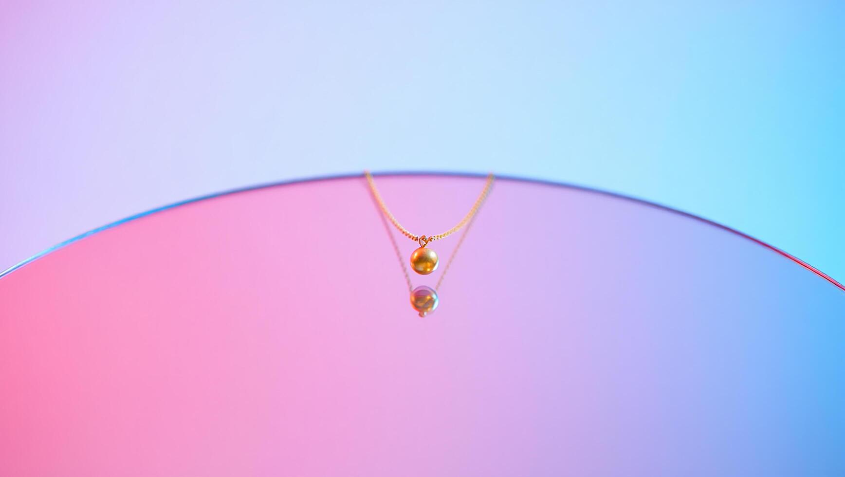 Elegant golden necklace displayed with soft lighting and gradated pink and blue background photo