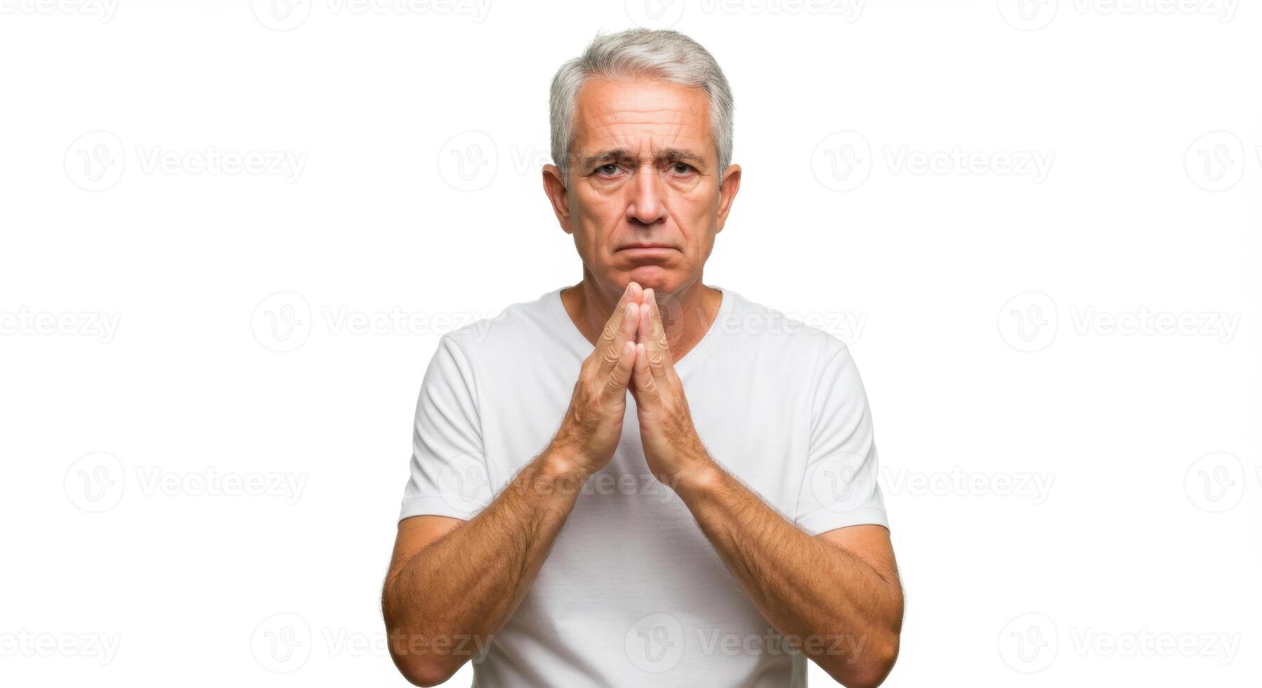Concerned Senior Man in White Shirt with Hands Clasped in Pleading Gesture on White Background photo