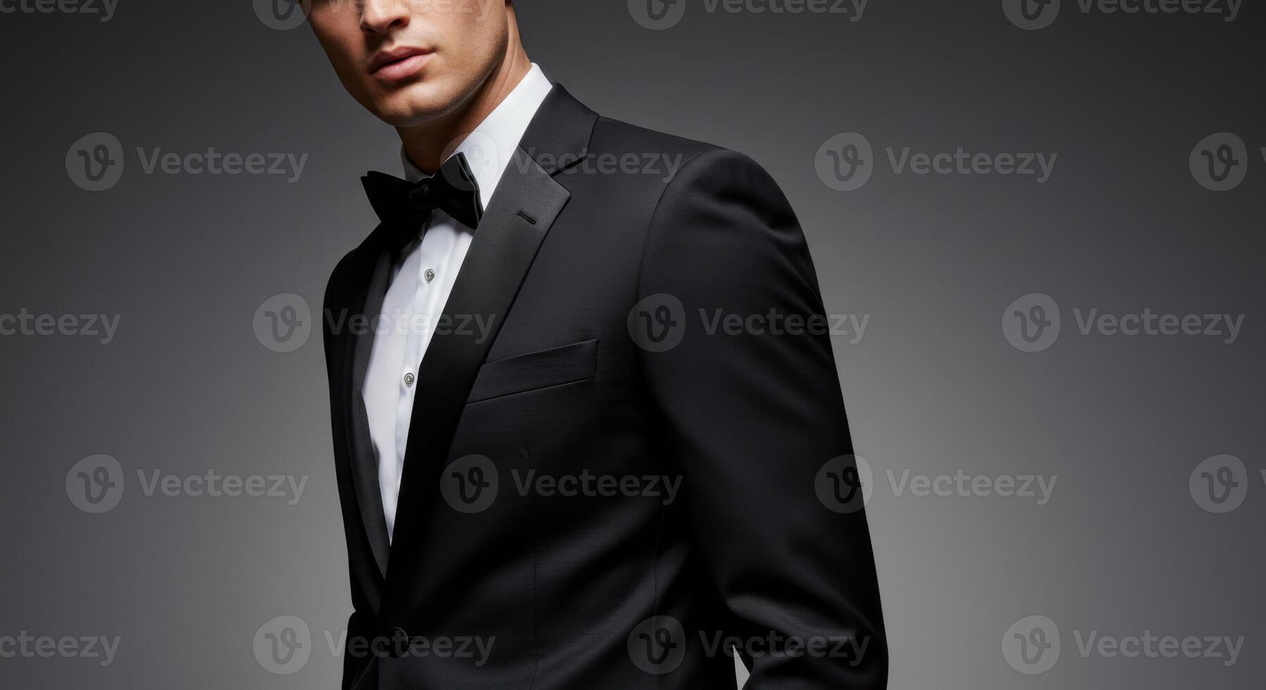Stylish Young Man in Black Tuxedo with Satin Lapel Against Dark Background photo