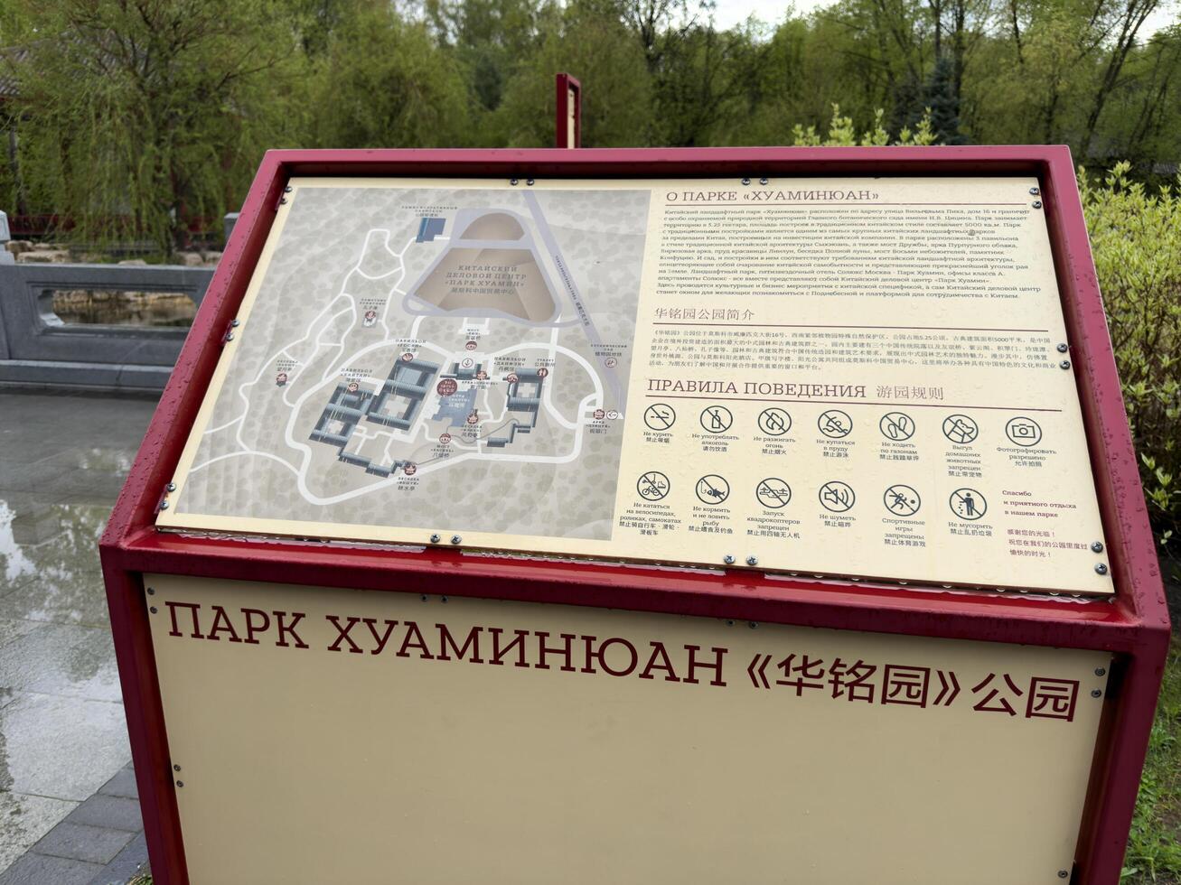 Moscow, Russia, April 25, 2025 Informational board with map and visitor rules at Huamin park in Moscow, designed in Chinese style and placed near scenic landscape and traditional architecture photo