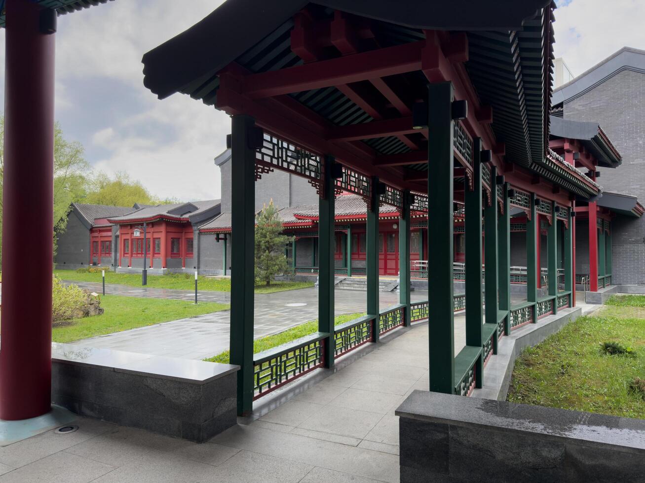 Moscow, Russia, April 25, 2025 Covered gallery in Chinese architectural style with red and green columns, decorative lattice panels and tiled roof, located in public cultural park in Moscow photo