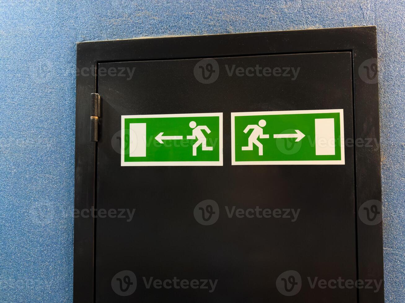 Universal exit signs with running figure and directional arrows illustrate internationally recognized emergency guidance system, offering nonverbal clarity across cultures in public buildings photo