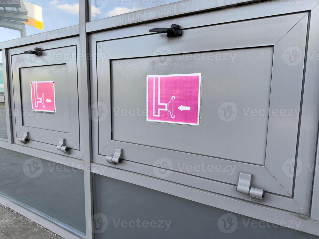 Metal fire hose cabinets with emergency signs and pictograms indicating hose reel direction, installed on building exterior as part of public fire safety system and modern infrastructure photo