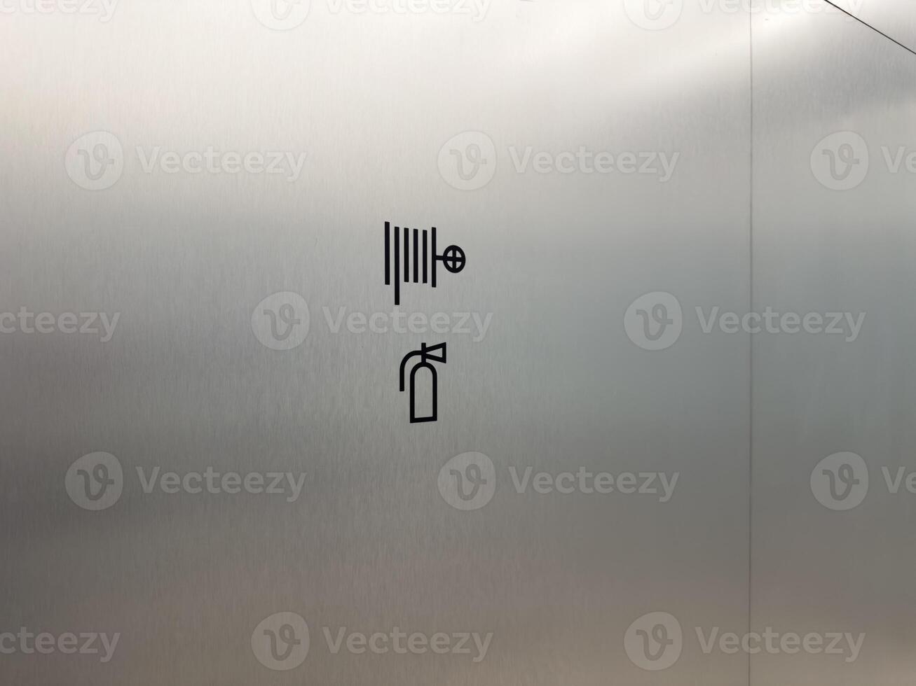 Wall mounted fire safety sign showing fire hose and extinguisher icon. Clean metal background emphasizes emergency equipment location. Concept of public safety and emergency preparedness photo