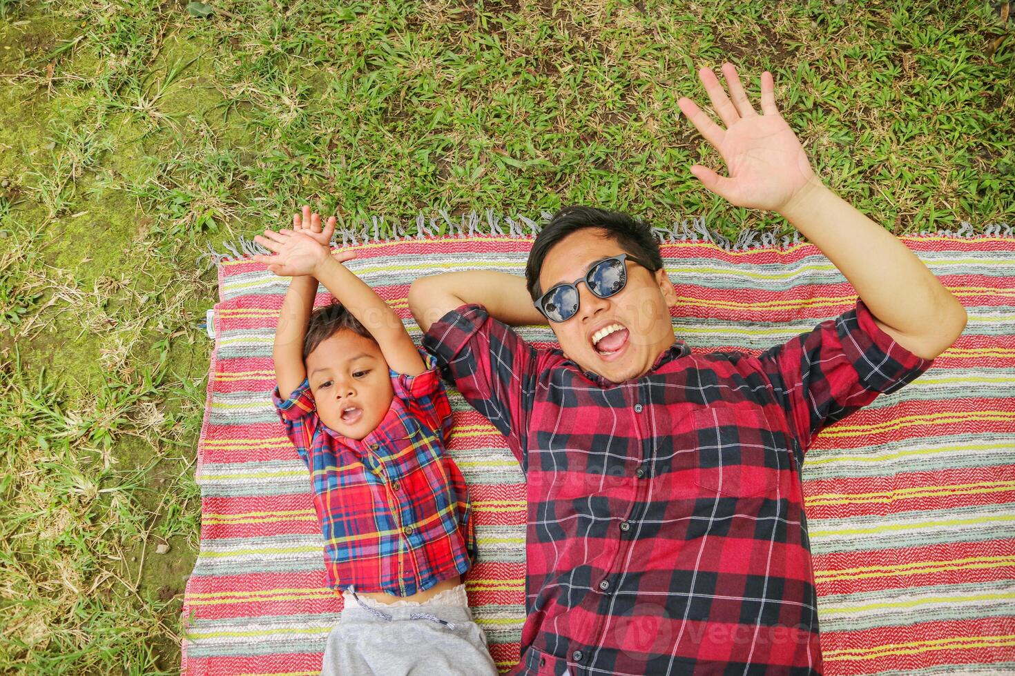 Happy father and son lying down on a picnic blanket photo