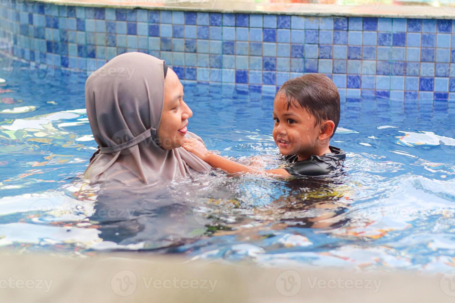 Happy mother and daughter playing in swimming pool photo