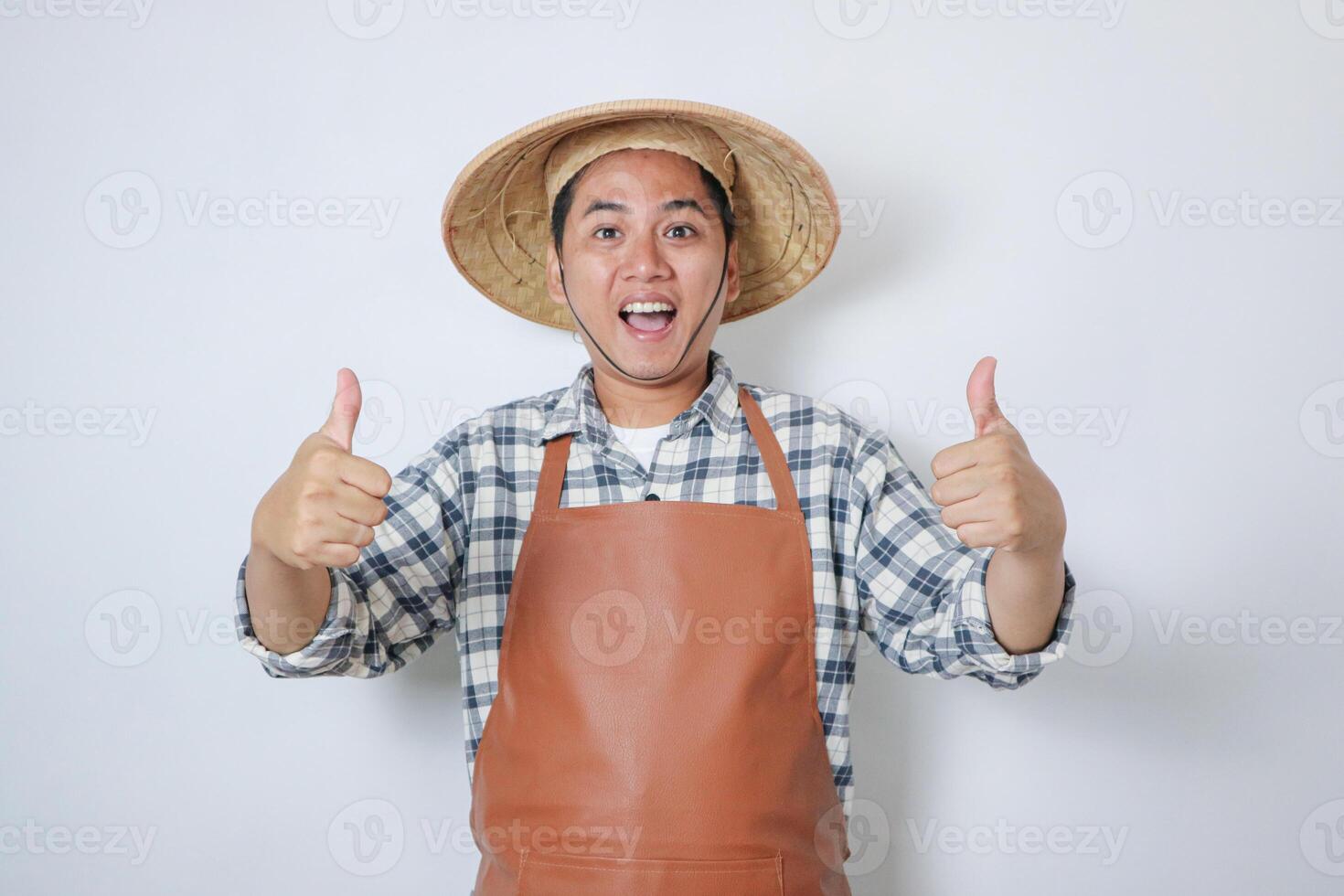 Indonesian farmer wearing conical hat showing happy expression while giving two thumb up. photo