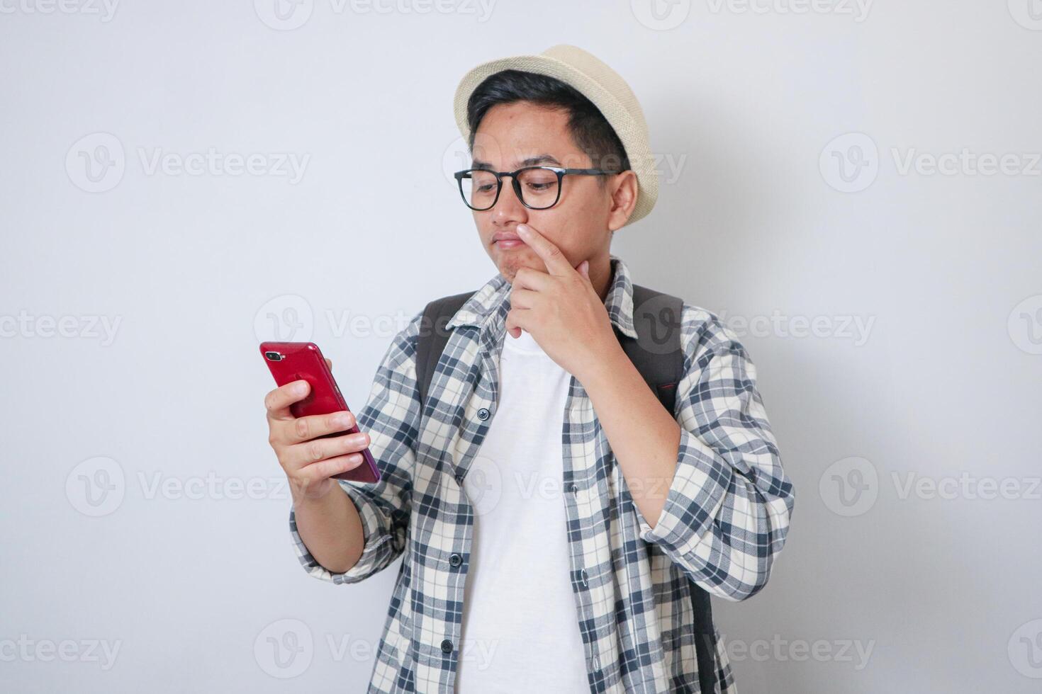 Traveler man hold mobile phone thinking about holiday isolated photo