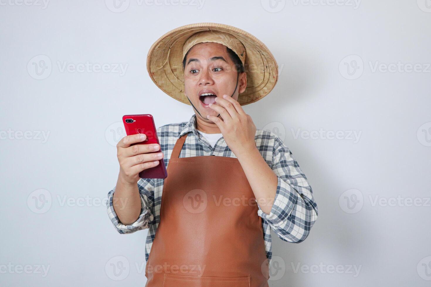 Indonesian farmer wearing casual shirt, apron and Caping showing shocked expression while calling someone photo