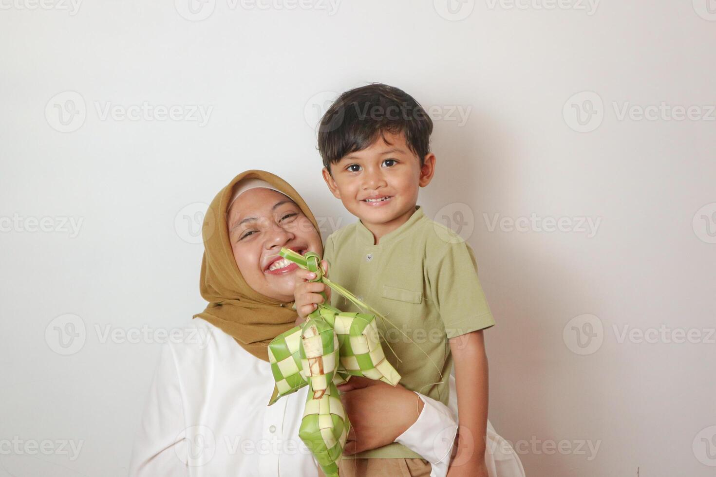happy asian muslim mother and son making ketupat together at home before eid mubarak photo