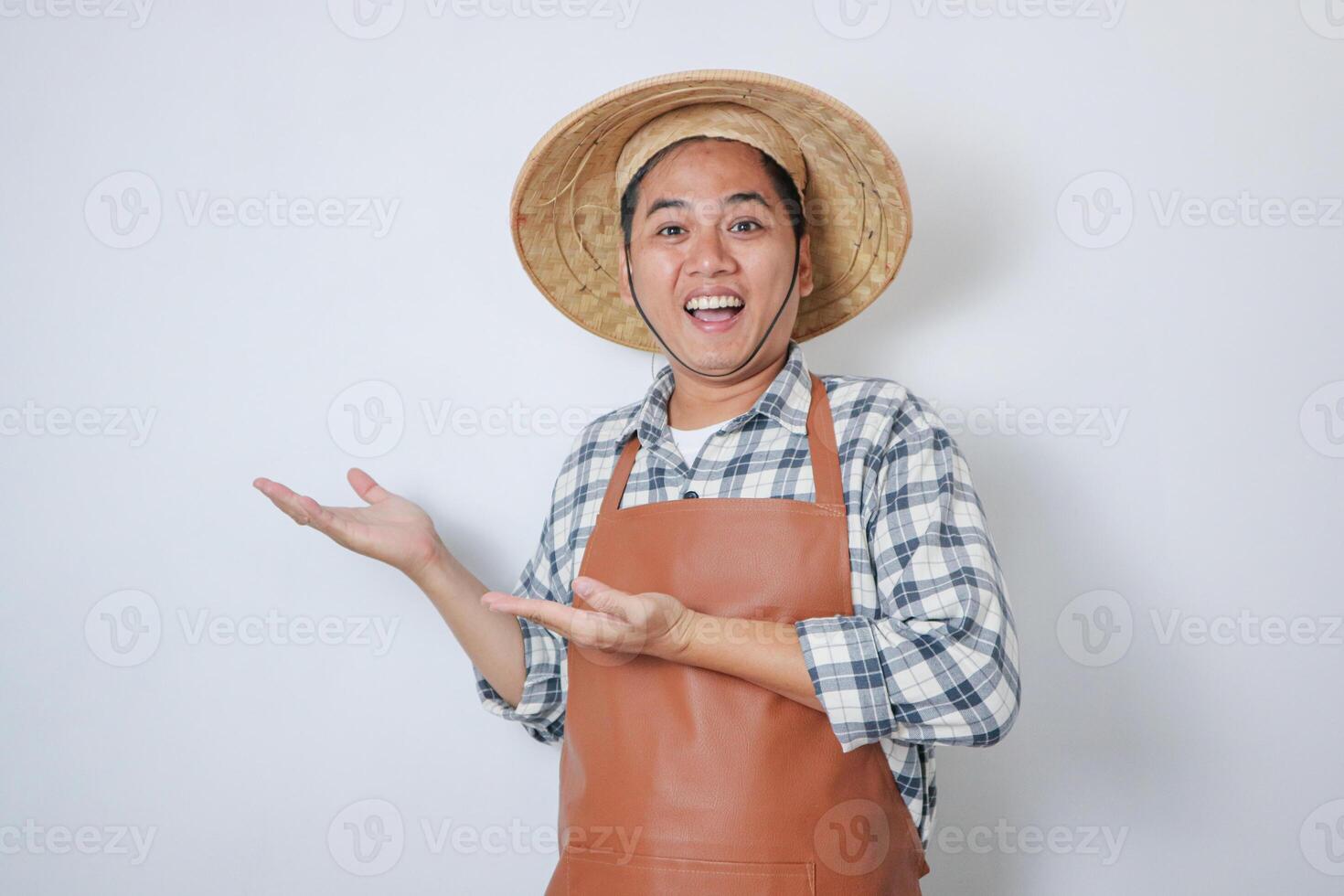 Adult Asian man wearing farmer hat showing happy face expression while his hand presenting something photo