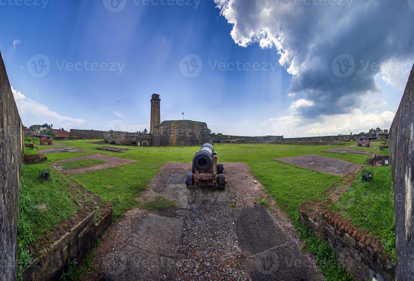 Old cannon and clock tower at Galle Fort with Sri Lankan flag, no people visible 3 photo