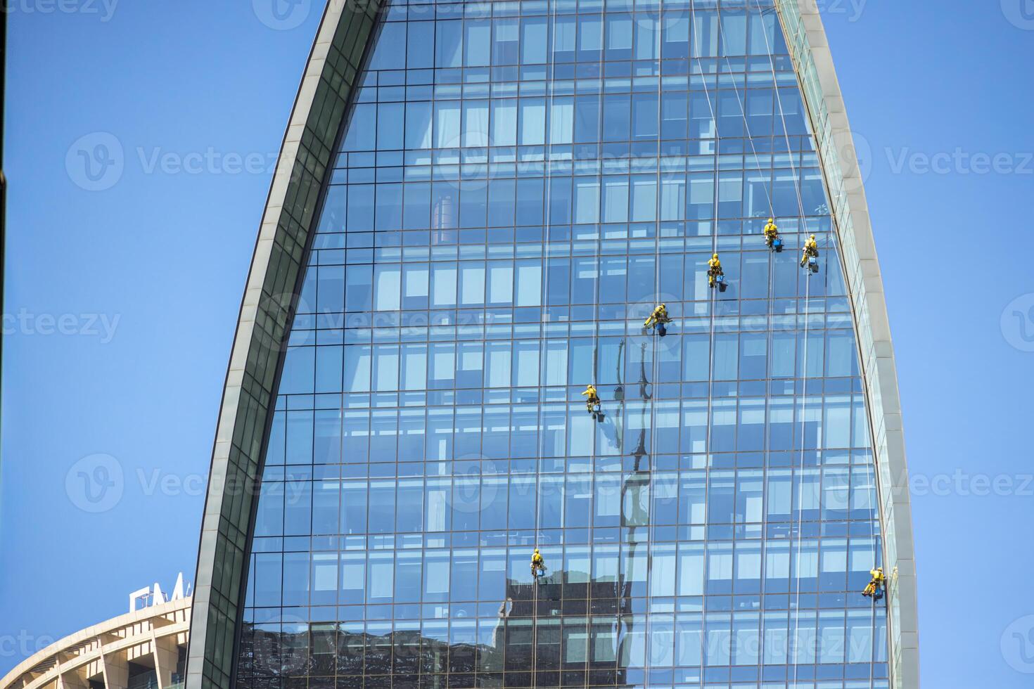 Rope access workers suspended while cleaning the glass facade of a modern highrise office building 2 photo