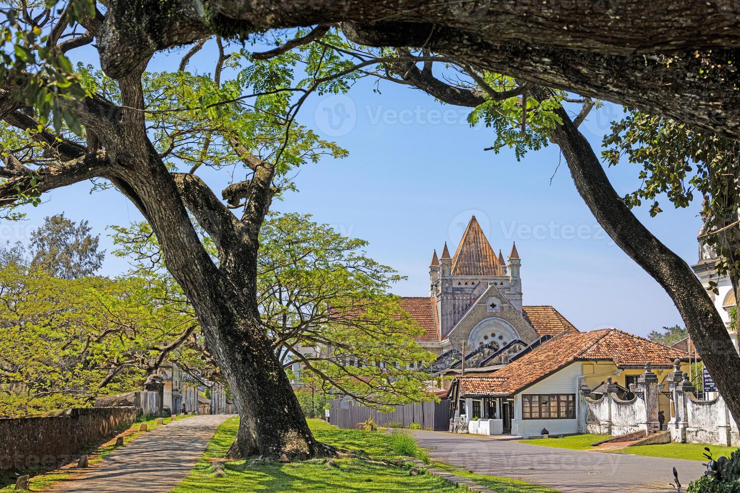All Saints Church in Galle Sri Lanka framed by old trees on a sunny day photo