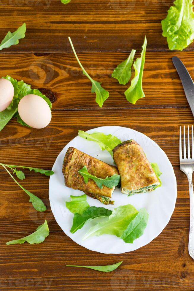 Quick and easy breakfast. Healthy egg roll with greens on a white plate photo