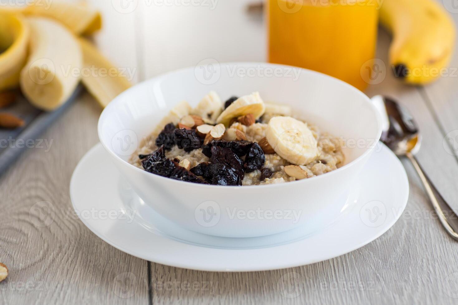 Quick and easy breakfast.Healthy oatmeal with banana, nuts and prunes photo