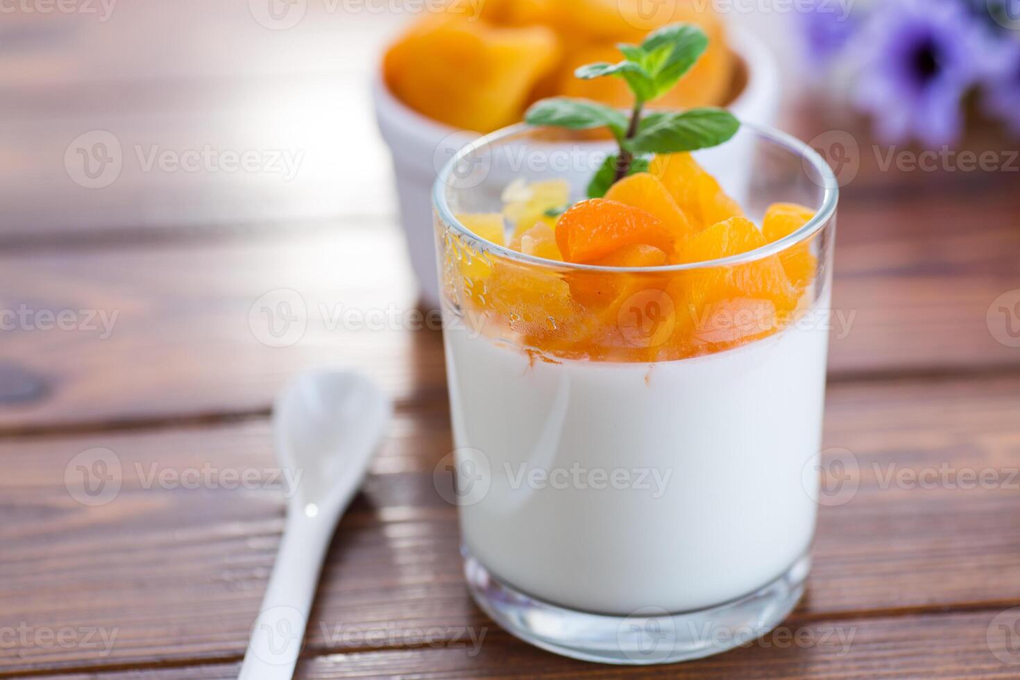 Light fruit yogurt with dried apricots on dark wooden table. Quick and easy breakfast. photo