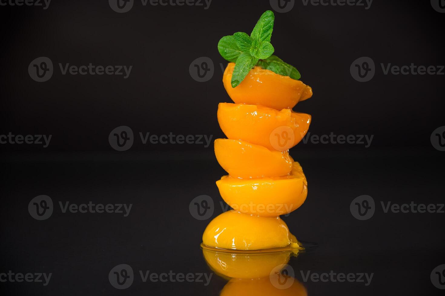 Canned apricot slices. Ripe peach halves in syrup on black background photo