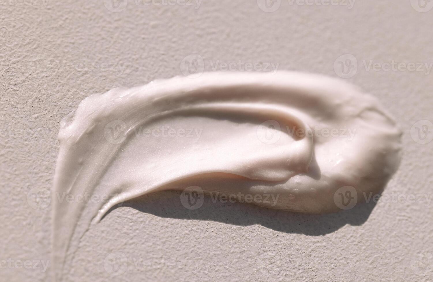 Close-up of the texture of pink cream on a light background. Moisturizing serum is smeared on the backdrop. The consistency of glycerin gel. Cosmetic smear. photo