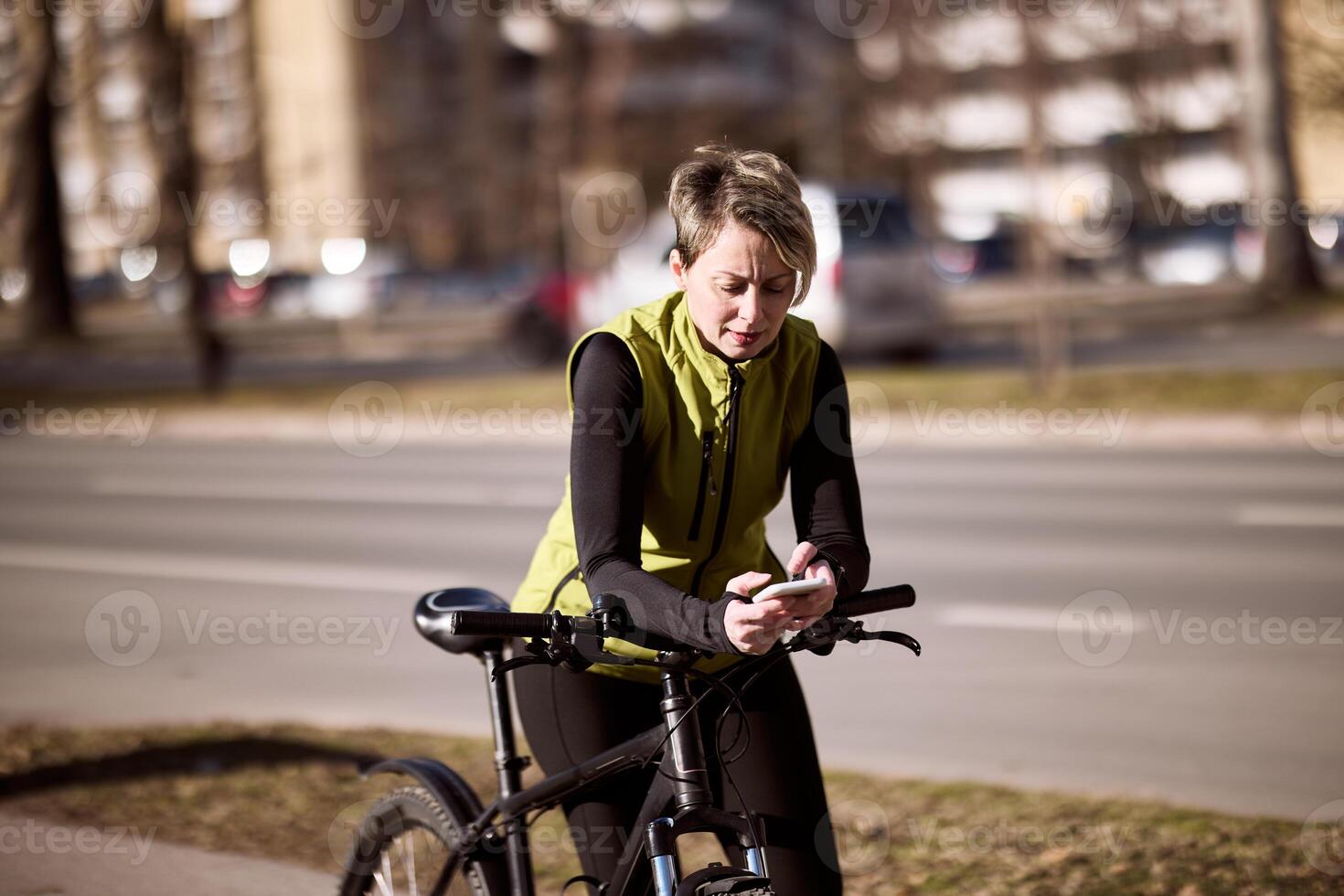 Woman Leaning to Bike Texting on Cell Phone photo
