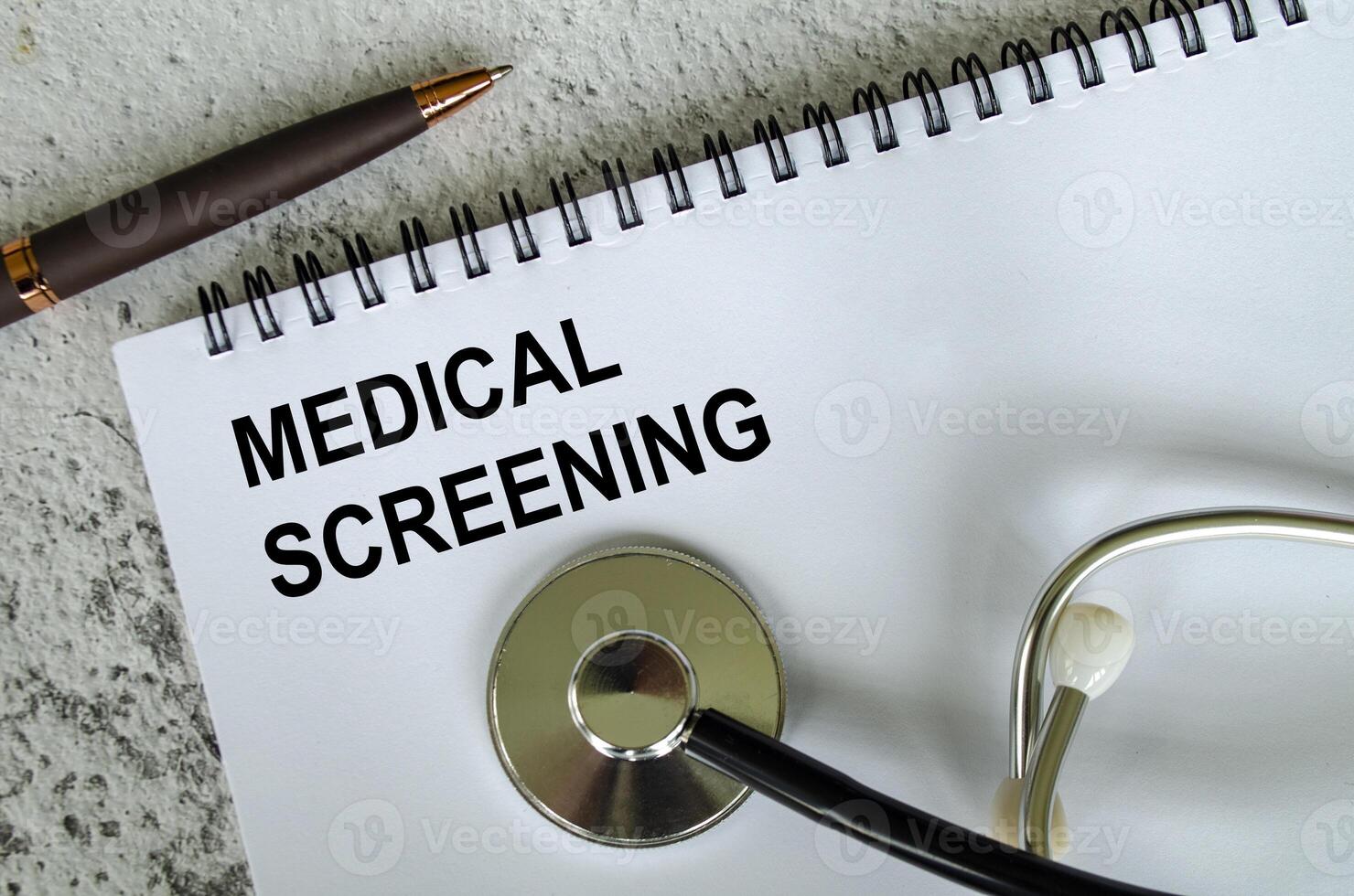 Top view of Medical Screening Text on white paper notepad with stethoscope on wooden table background. Health and medical concept. photo
