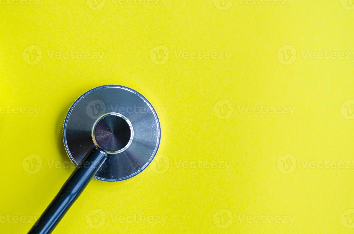 A stethoscope placed on a bright yellow background with customizable space for text. photo